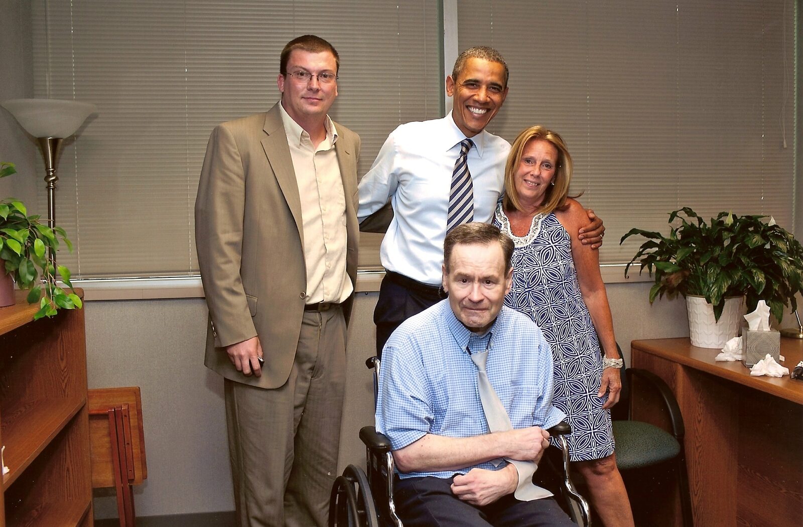 President Barack Obama, Lane Evans, Devin Hansen in a tan suit, and Cher Erickson, Lane's caretaker, in a small office, 2011.