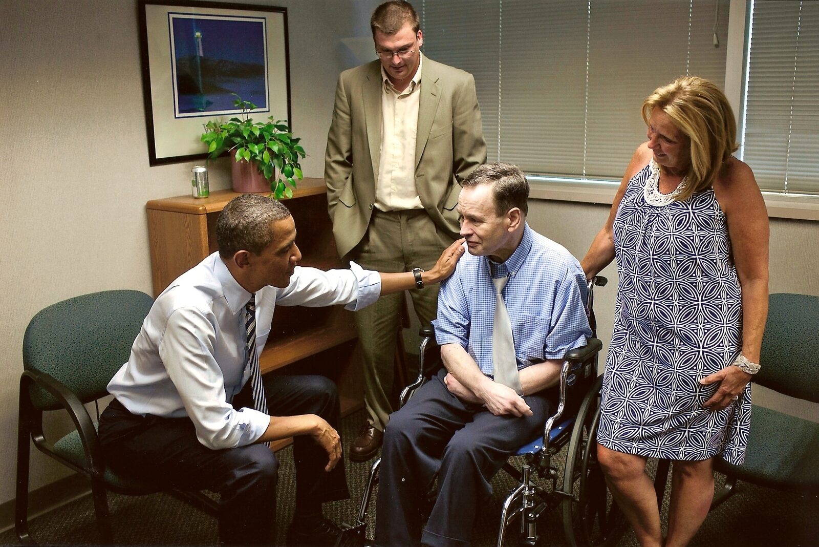 President Barack Obama, seated, leans in to talk with a man in a wheelchair while Devin Hansen and a woman look on, 2011.